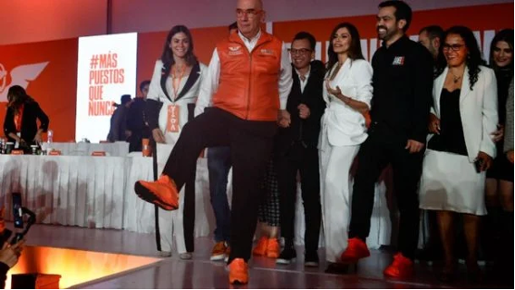 Un grupo de personas paradas en un escenario con zapatos naranjas.