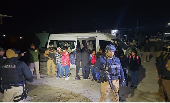 Un grupo de personas paradas frente a una furgoneta por la noche.