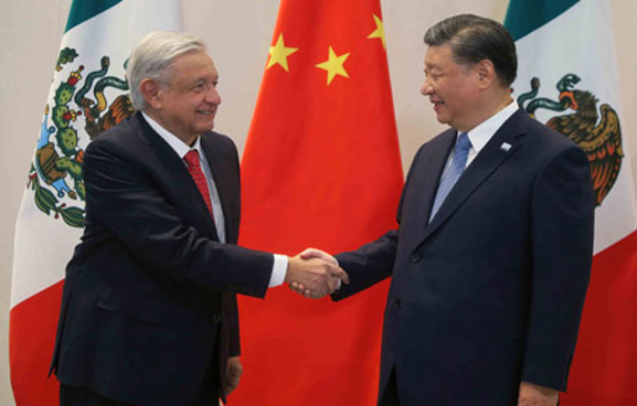 Dos hombres dÃ¡ndose la mano frente a banderas mexicanas y chinas.