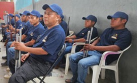 Personal uniformado sentado en fila con porras.
