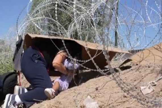 Una mujer se esconde bajo una valla de alambre de pÃºas.