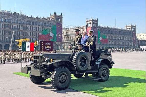 Dos hombres en un jeep militar frente a una gran multitud.