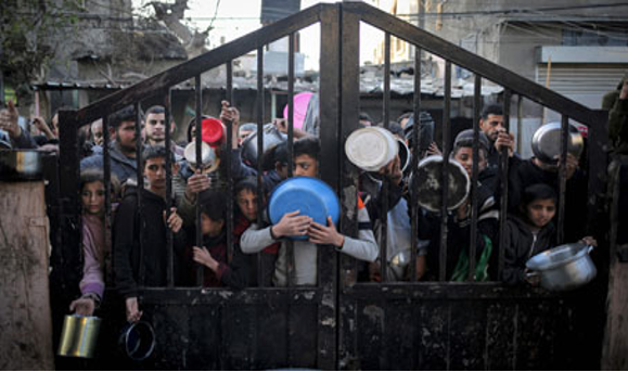 Personas esperando con contenedores detrás de una puerta, posiblemente para distribución de alimentos.