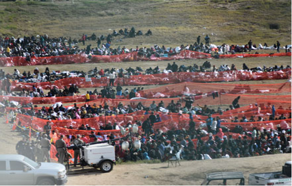 Un grupo de personas paradas en un campo cerca de un camión.