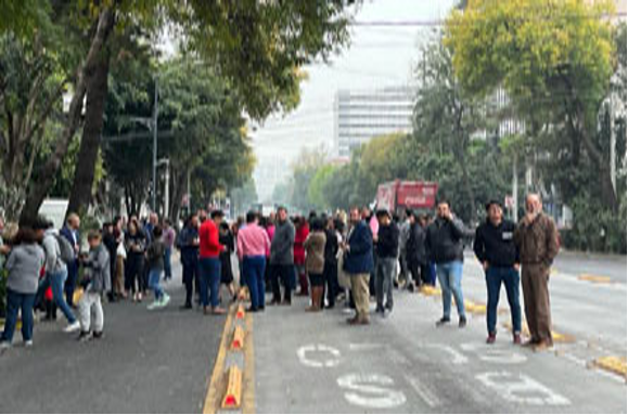 Un grupo de personas paradas al costado de una calle.