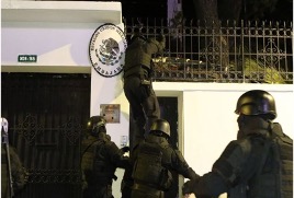 Un oficial de policía con equipo táctico salta una valla con la ayuda de otros agentes durante una operación nocturna.