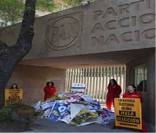 La gente se encuentra frente a la sede del "Partido Acción Nacional" con carteles y un montón de pancartas políticas desechadas.