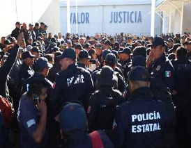 Una multitud de policías uniformados se reunió frente a un edificio que tenía escrito "Valor Justicia" en la pared.