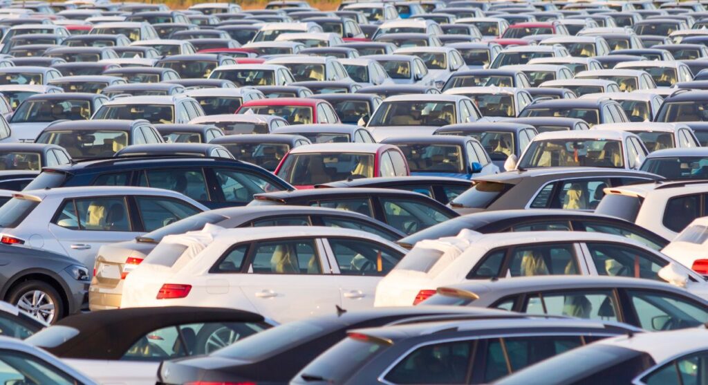 Un gran estacionamiento repleto de filas apretadas de varios vehÃ­culos usados importados, principalmente plateados y blancos, vistos desde una ligera elevaciÃ³n.