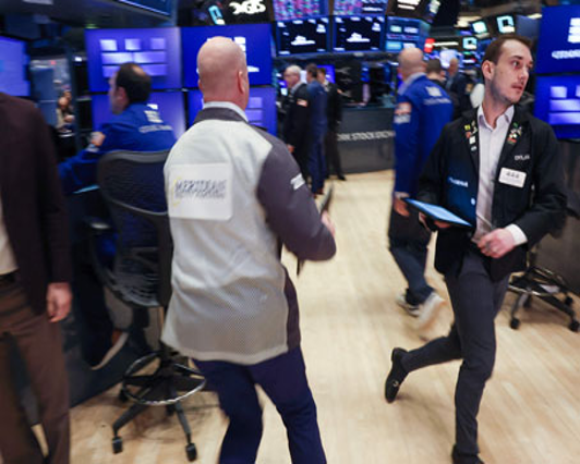 Los comerciantes se mueven a través de un bullicioso piso de la Bolsa de Valores, lleno de pantallas y actividad.