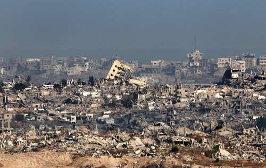 Una vista amplia del paisaje urbano muestra una destrucción extensa, con numerosos edificios derrumbados o gravemente dañados y escombros esparcidos por toda el área.
