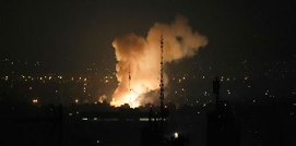 Gran explosión con humo elevándose sobre una ciudad por la noche; luces de la ciudad y estructuras recortadas visibles en primer plano.