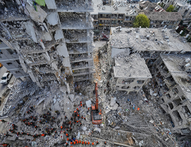 Vista aérea de trabajadores de rescate y maquinaria entre los escombros de los edificios derrumbados después de un desastre.