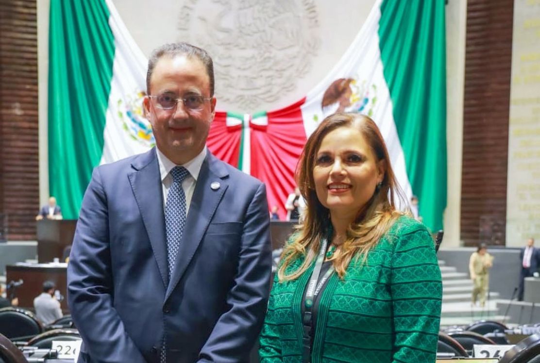 Un hombre y una mujer delante de unas banderas.