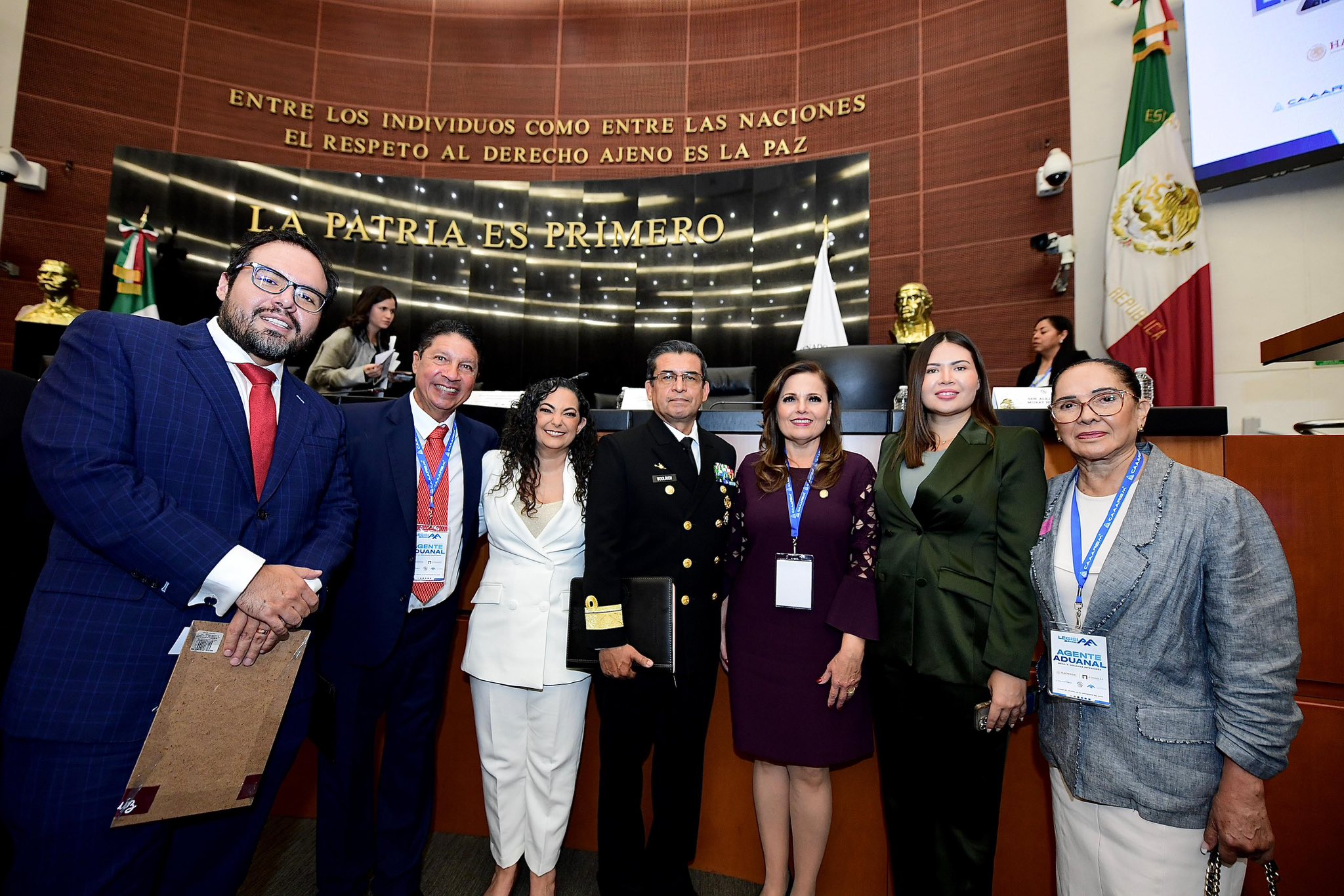 Siete personas posan para una foto de grupo en un salón oficial del gobierno, con placas oficiales y la bandera mexicana a la vista, destacando a los líderes en exportación y logística.