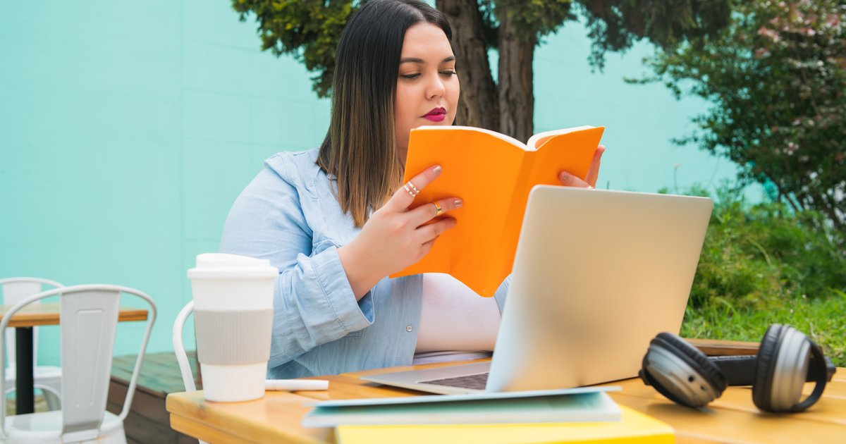 Joven estudiando con laptop y libros en una cafetería